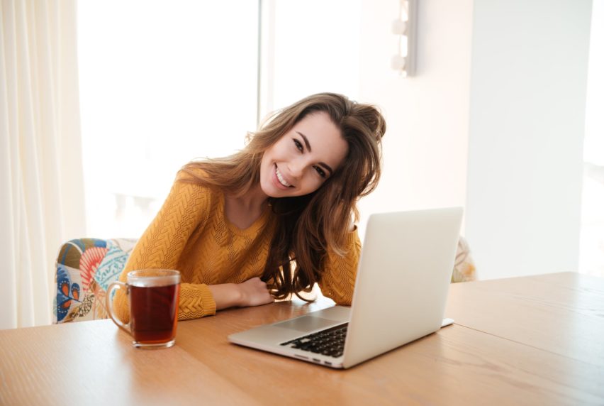 Portrait of a smiling young woman working on laptop at home