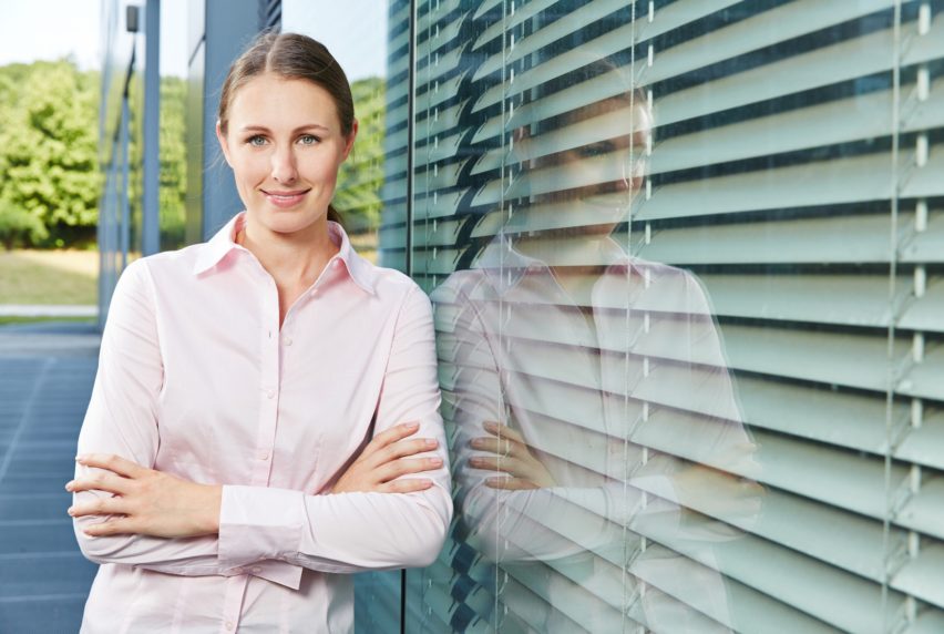 Young business woman standing next to the office with her arms crossed